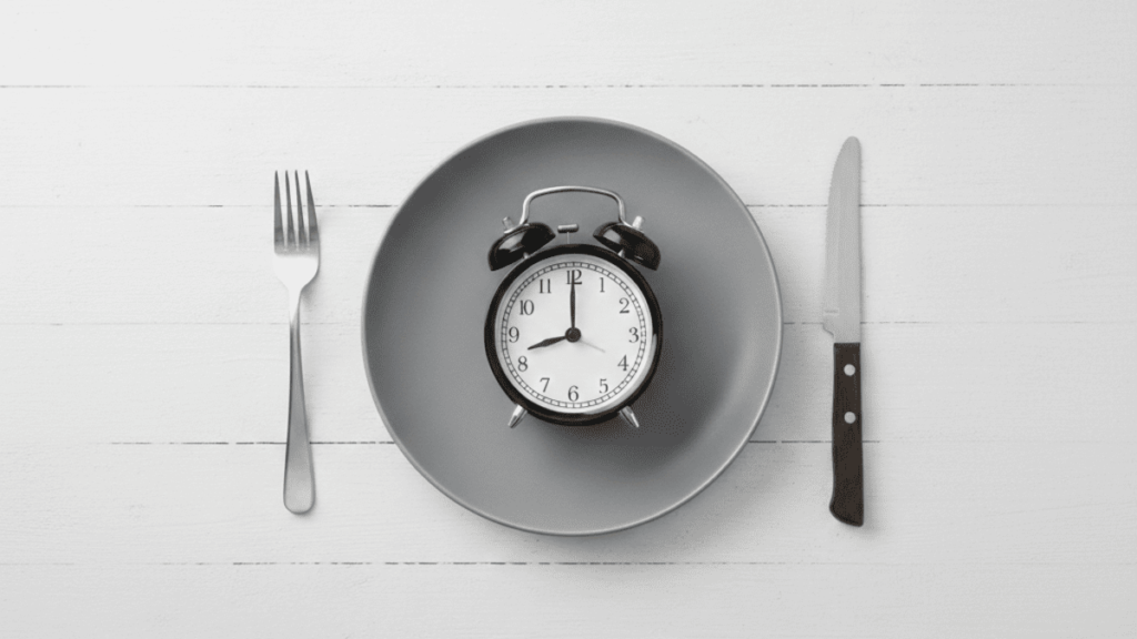 プレートの上に目覚まし時計を置き、16時間断食（時間制限食）をイメージした画像