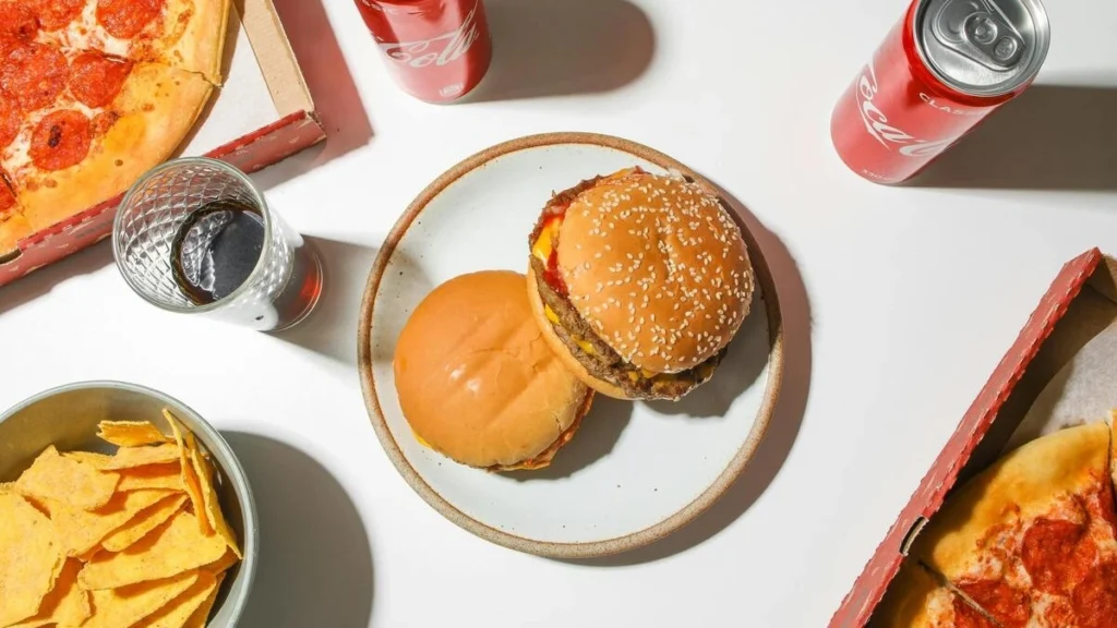 ジャンクフードが白いテーブルに並んでいる画像