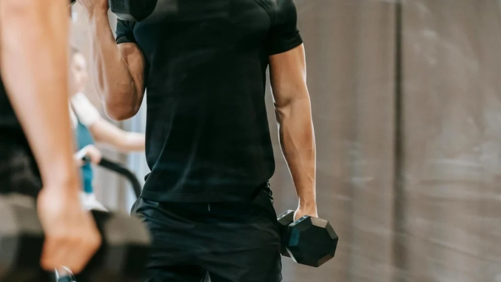 男性が鏡の前でダンベルカールをしている画像