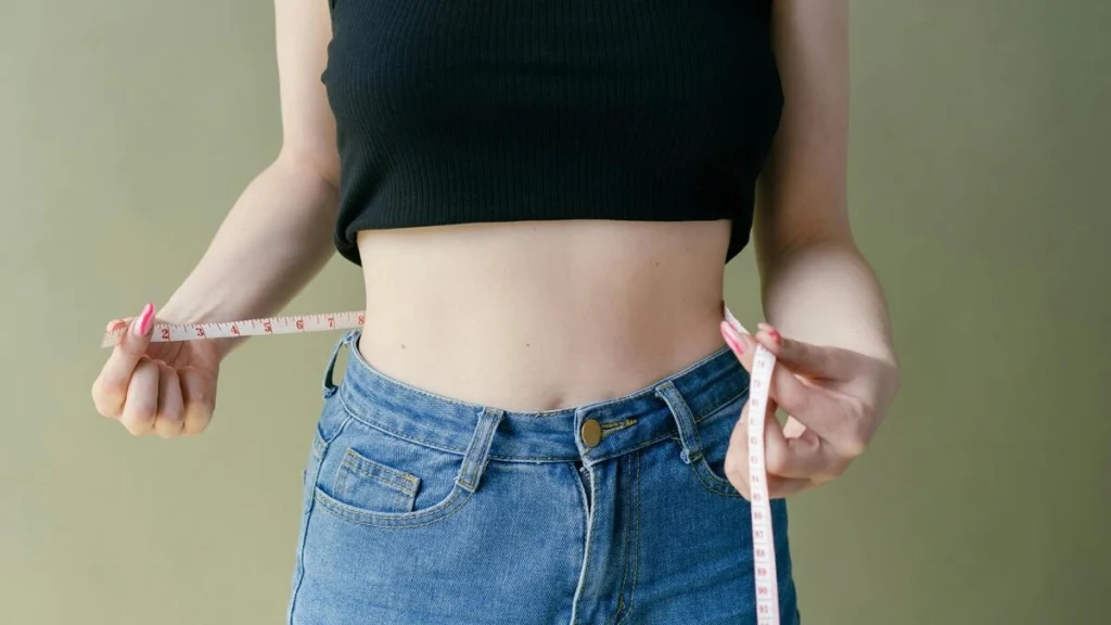 女性がウエストをメジャーで測っている画像